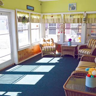 A bright sunroom with wicker furniture and large windows allowing natural light to fill the space.