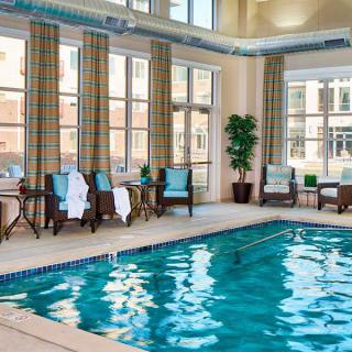 A tranquil indoor swimming pool with seating and towels.