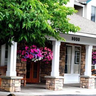 A charming building entrance with white columns and hanging floral arrangements.