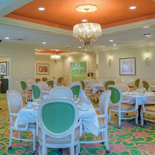 An elegant restaurant dining room with green and white furniture and a chandelier.