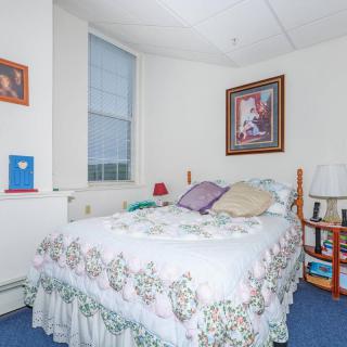 Cozy bedroom with a floral bedspread, pillows, and framed artwork on the wall.