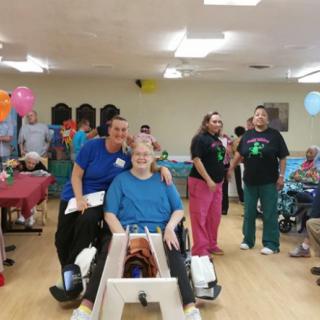 A group of people indoors, celebrating with balloons and smiles in a healthcare setting.