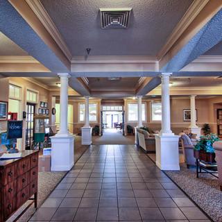 A spacious lobby with columns and furniture arranged on a tiled floor.