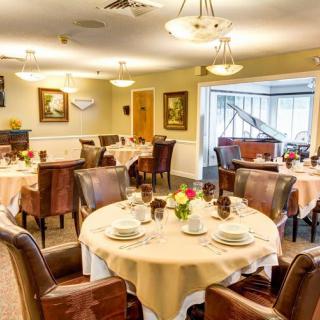Elegant dining room setup with round tables and comfortable chairs, adorned with decorative elements and warm lighting.