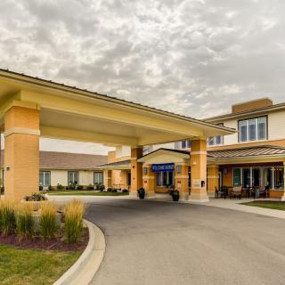 A modern building with an inviting entrance and a driveway under a cloudy sky.