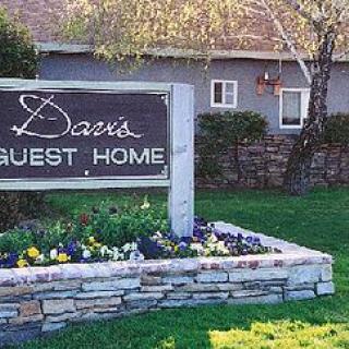 A sign for a guest home surrounded by a small landscaped garden.