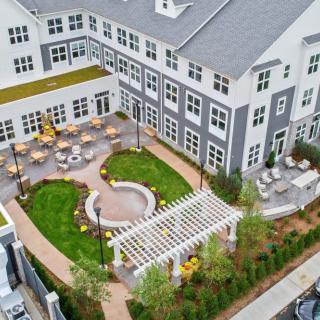 Aerial view of a residential complex with a landscaped courtyard featuring outdoor seating and garden areas.