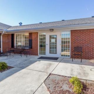 A brick building entrance with double glass doors and benches on either side.