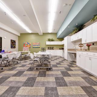 Modern kitchen and dining area with white cabinets and tiled flooring.
