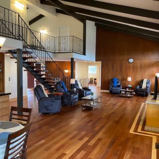 A spacious and modern living room with wooden floors, high ceilings, and a mezzanine loft area.