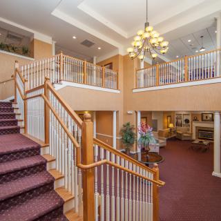 A spacious interior lobby with a grand staircase, ornate chandelier, and comfortable seating.
