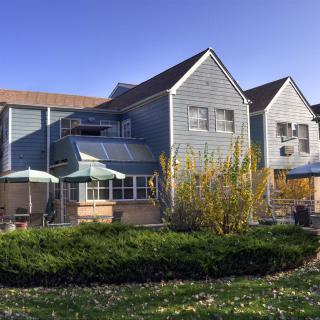 A suburban two-story house with a garden under a clear blue sky.