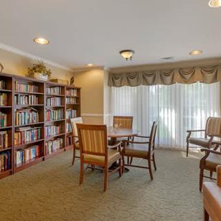A cozy library space with bookshelves, a table, and chairs for reading.