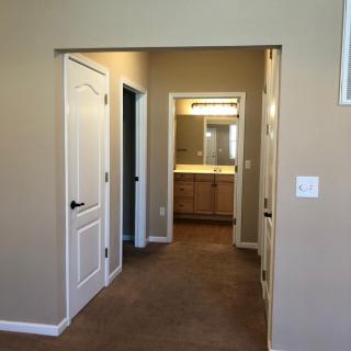 A view of a home's hallway leading to a bathroom with warm lighting.