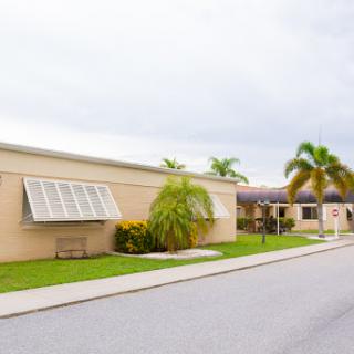 A view of a pleasant residential building with palm trees lining the street.