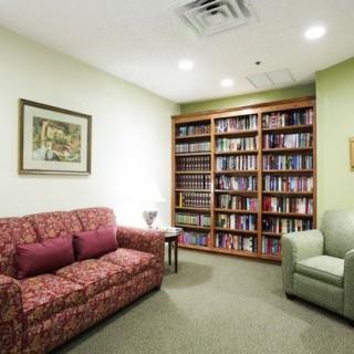 A cozy library room with a sofa and bookshelves filled with books.
