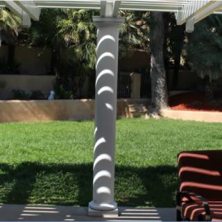 Sunlight creates curved shadows on a column in a garden patio.
