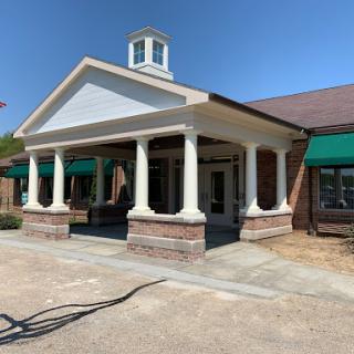 A nicely designed entrance of a building with classical columns under a clear blue sky.