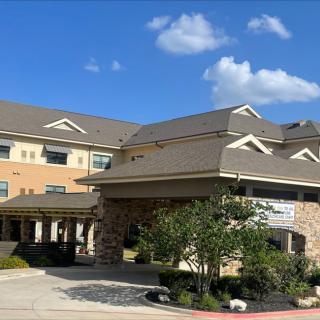 A hotel building under a clear blue sky with scattered clouds.