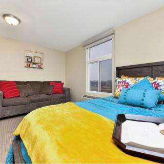A cozy bedroom with a colorful bedspread, decorative pillows, and a comfortable sofa.