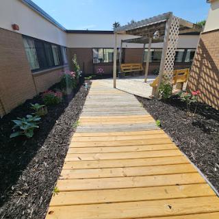 A wooden walkway leading through a landscaped garden under a clear blue sky.