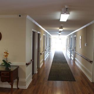 A well-lit hallway with wooden flooring and several doors.