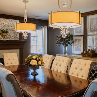 A beautifully designed dining room featuring elegant chandeliers, a wooden table, and tasteful floral arrangements.