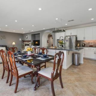 A modern open-concept dining and kitchen area with elegant furniture and stainless steel appliances.