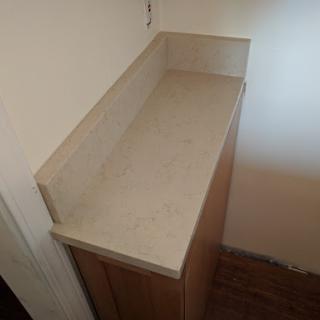 A clean, unfinished kitchen countertop with wooden cabinets below.