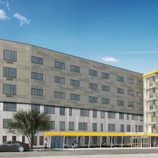 A modern hotel building featuring sleek architectural design and spacious windows under a clear blue sky.