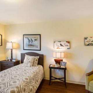 A cozy bedroom with a single bed, two lamps, and decorative wall art.