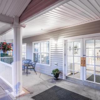 A welcoming building entrance with a porch, seating area, and decorative plants.