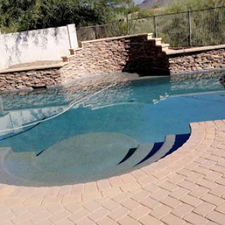 A serene outdoor pool with a stone backdrop, perfect for relaxation.