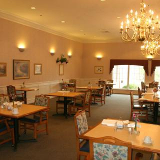 A cozy dining room with elegant chandeliers and neatly arranged tables and chairs.