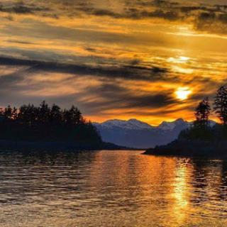 A breathtaking sunset casting golden hues over tranquil waters, framed by distant mountains.