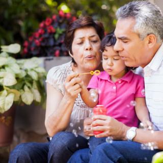 A child enjoying bubble time with grandparents in the garden.