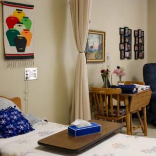 A cozy hospital room with a bed, table, and decorative artwork.