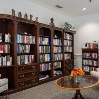 A cozy library reading room with wooden bookshelves filled with books and comfortable seating.