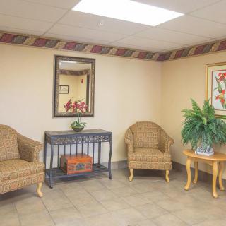 A cozy waiting room with wicker chairs and a decorative mirror.