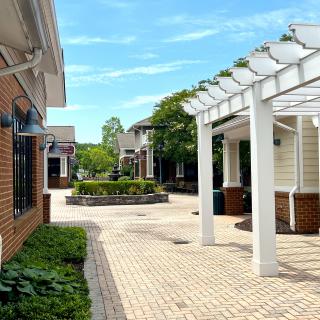 A sunny day at a charming outdoor shopping center with brick buildings and a white pergola.