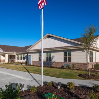 A single-story building with an American flag in front on a clear day.