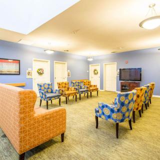 A brightly lit living room with colorful chairs arranged in front of a television, set against blue walls.