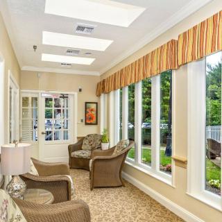 A bright and inviting sunroom with large windows, wicker chairs, and warm lighting.