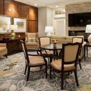 A cozy living room with elegant furniture, including a central round table with chairs, a sofa, and a fireplace with a mounted television.