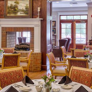 A cozy dining area with elegantly set tables and a warm fireplace.