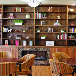 A cozy library space featuring wooden bookshelves, a fireplace, and comfortable chairs.