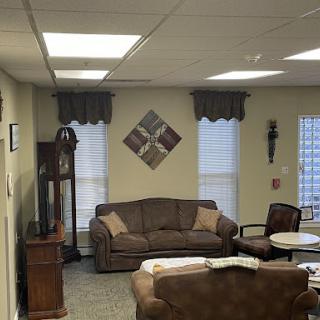 A cozy living room featuring a comfortable sofa, an antique clock, and decorative window treatments.