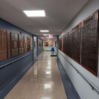 A view of a hallway lined with wooden plaques, showcasing achievements or honors.