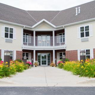 A two-story building with a central entrance, surrounded by vibrant landscaping.