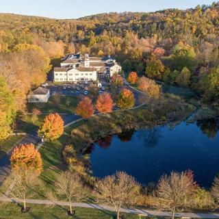 A picturesque aerial view of an estate surrounded by autumn foliage and a tranquil lake.